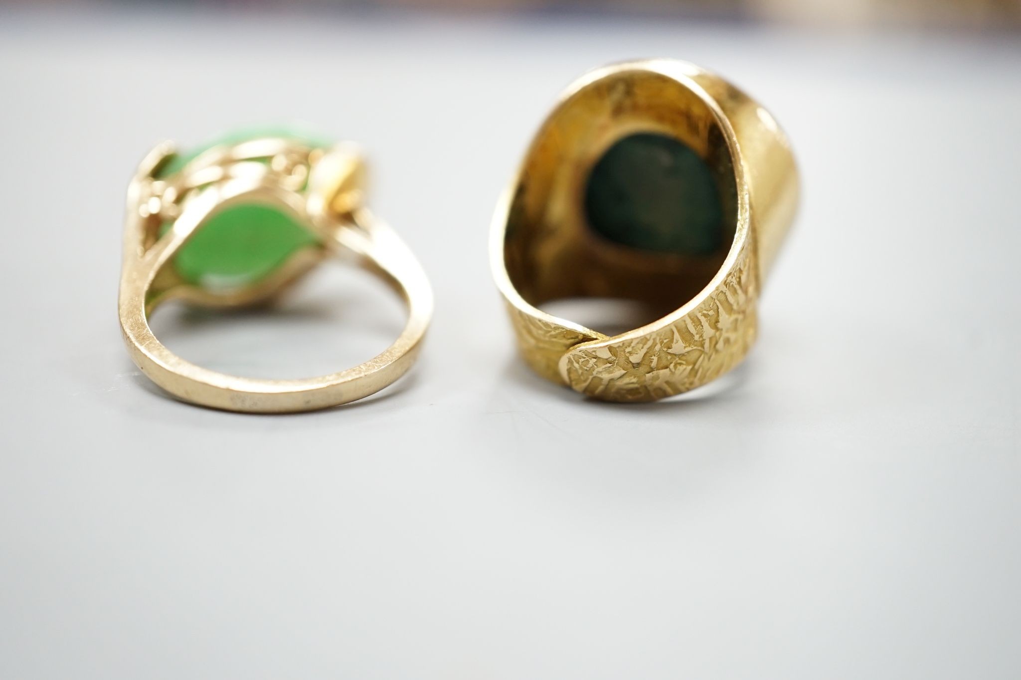 A modern 14k yellow metal and cabochon malachite set dress ring, size F and a similar cabochon jade set ring, size K, gross weight 16.8 grams.